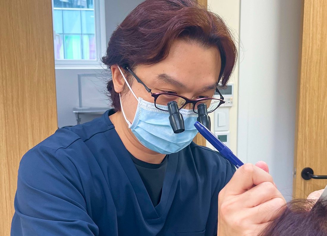 허준모 원장이 환자 머리에 헤어라인을 표시하는 진료 장면